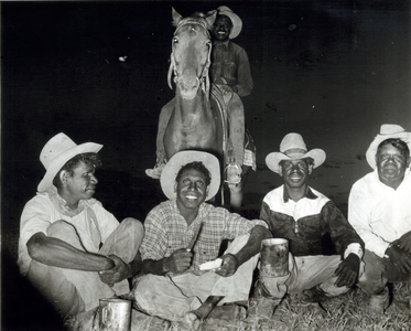 Group of five Aboriginal stockmen on horseback at night camp.